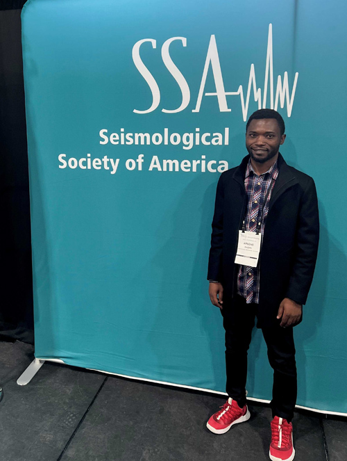 Arsene Sadiki in front of teal sign for 2024 SSA Annual Meeting