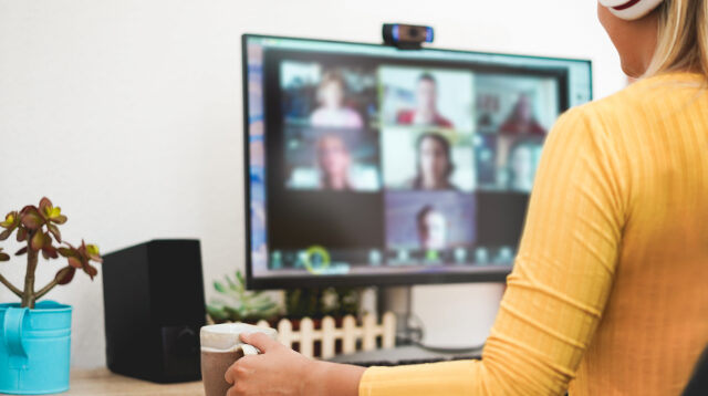 A view of a Zoom call, looking over the shoulder of a person wearing a yellow top.