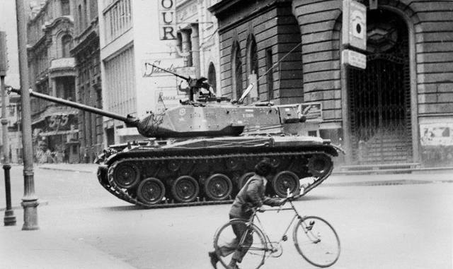 child with his bicycle running away from a military tank moving towards La Moneda presidential palace